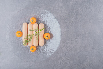 A glass plate of boiled sausages with cherry yellow tomatoes