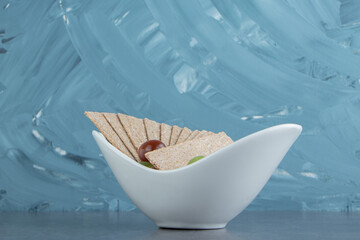 A white bowl full of rye crispy cereals and colorful tomatoes