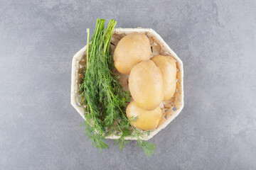 A white plate of uncooked potatoes with fresh dill