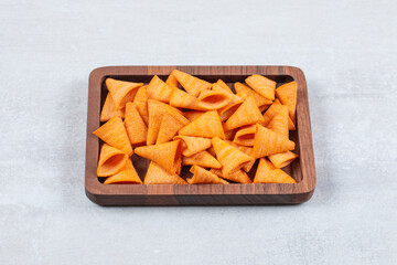 Delicious crunchy chips on wooden plate