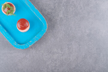 Sliced sausages with ketchup on blue wooden board