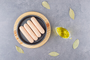A black plate of boiled sausages with oil