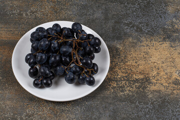 Cluster of black grapes on white plate