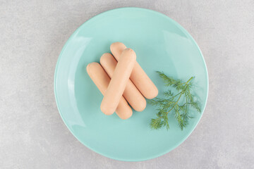 Boiled sausages and parsley on blue plate