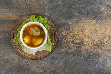 Bowl of soup with meatballs on wooden board