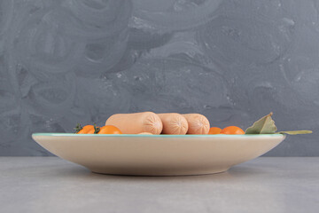 Homemade boiled sausages and tomatoes on blue plate