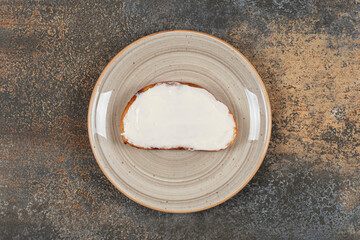 Slice of toast with sour cream on ceramic plate