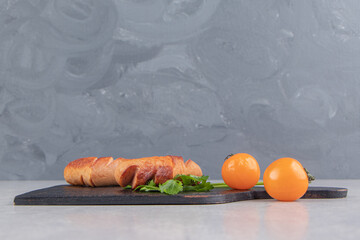 Grilled sausages with tomatoes on wooden board