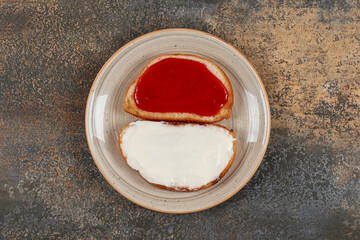 Toasts with strawberry jam and sour cream on ceramic plate