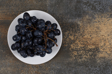Cluster of black grapes on white plate