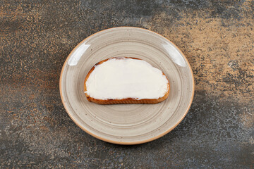 Slice of toast with sour cream on ceramic plate