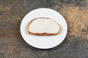 Slice of toast with sour cream on white plate