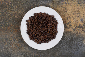 Aromatic coffee beans on white plate