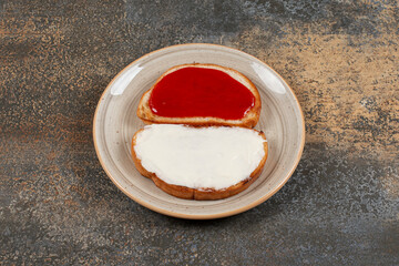 Toasts with strawberry jam and sour cream on ceramic plate