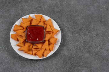 Triangle shaped chips and ketchup on white plate