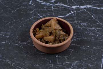 Marinated fresh vegetable salad in potter bowl over black stone background