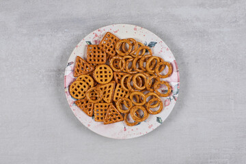 Plate of various salty crackers on stone background