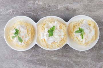 Spaghetti, yogurt and green vegetable on the plate , on the marble background