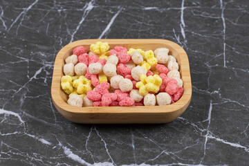 Colored cereal balls on wooden plate