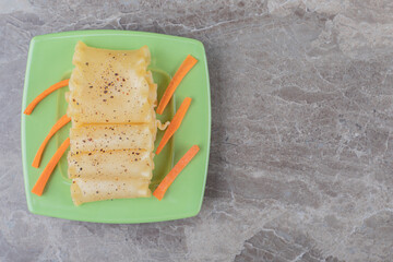 Spicy lasagna sheets alongside finely chopped carrots on the plate, on the marble background