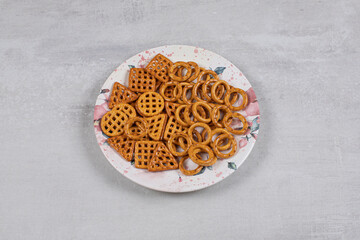 Plate of various salty crackers on stone background