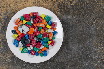 Multicolored stone candies on white plate