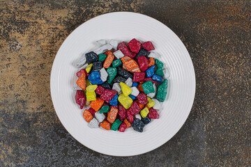 Multicolored stone candies on white plate