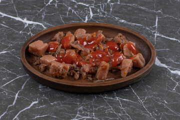 A wooden plate with boiled meat and ketchup
