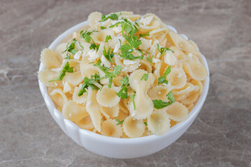 Toothsome farfalle pasta with greens on a bowl , on the marble background