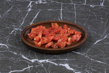 Wooden plate of sliced tomatoes on marble background