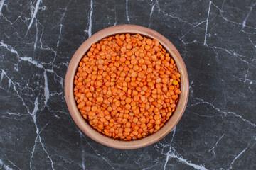 Fresh raw Lentils in bowl over black stone background