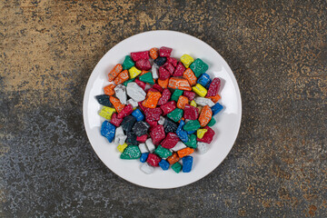 Multicolored stone candies on white plate