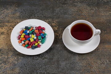 Plate of candies and hot tea on marble background