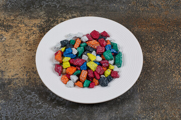 Multicolored stone candies on white plate