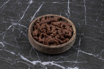 Chocolate cereal flakes in wooden bowl