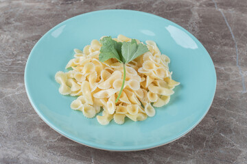 Farfalle pasta with greens on the plate , on the marble background