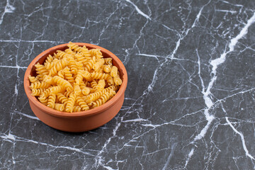 Pottery bowl full with raw spiral pasta