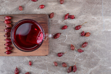 Rosehip tea ands rosehip fruit on the board, on the marble background