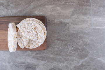 A stack of puffed rice cakes on the wooden tray, on the marble background