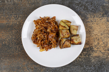 Fried eggplant rolls and onions on white plate