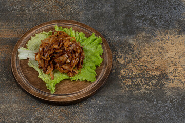 Fried onions with lettuce on wooden board