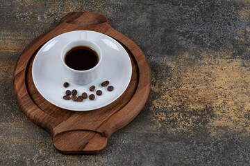 Cup of espresso with coffee beans on wooden board