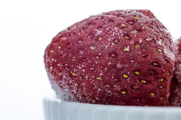 frozen strawberry in white ceramic bowl on white background with copy space 