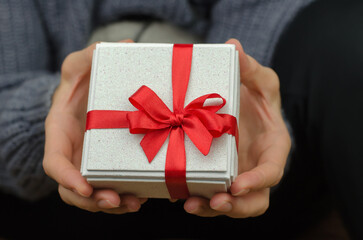 Gift box in female hands, close-up. Woman with white small gift box
