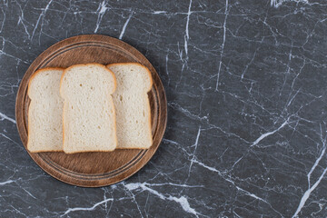 Fresh bread slices on wooden cutting board