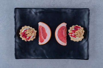Fresh cookies with grapefruit slices on black plate