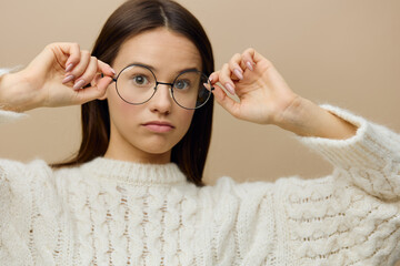 a beautiful woman stands on a light background of a white sweater with surprise puts on glasses, eyes wide open