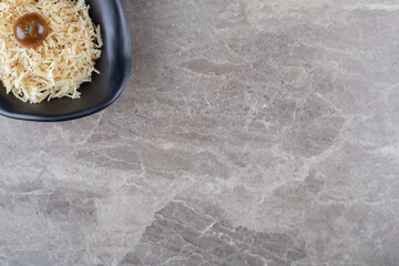 A bowl of grated pasta with tomato, on the marble background