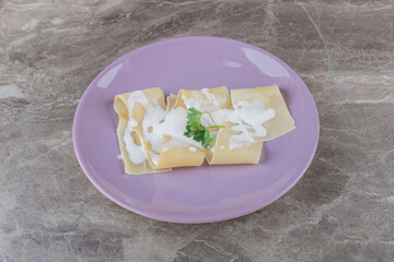 Flavorful yogurt on lasagna sheets with greens on the plate, on the marble background