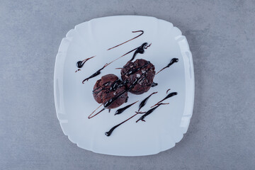 Two fresh chocolate muffin on white plate